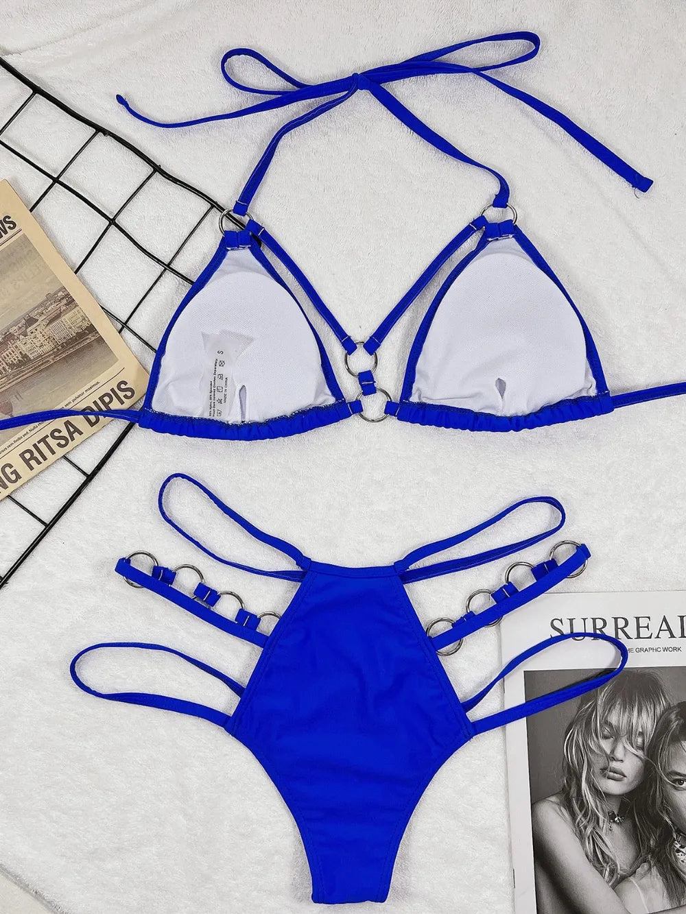 Pink cutout halter bikini top and matching ring-detail bottoms laid flat