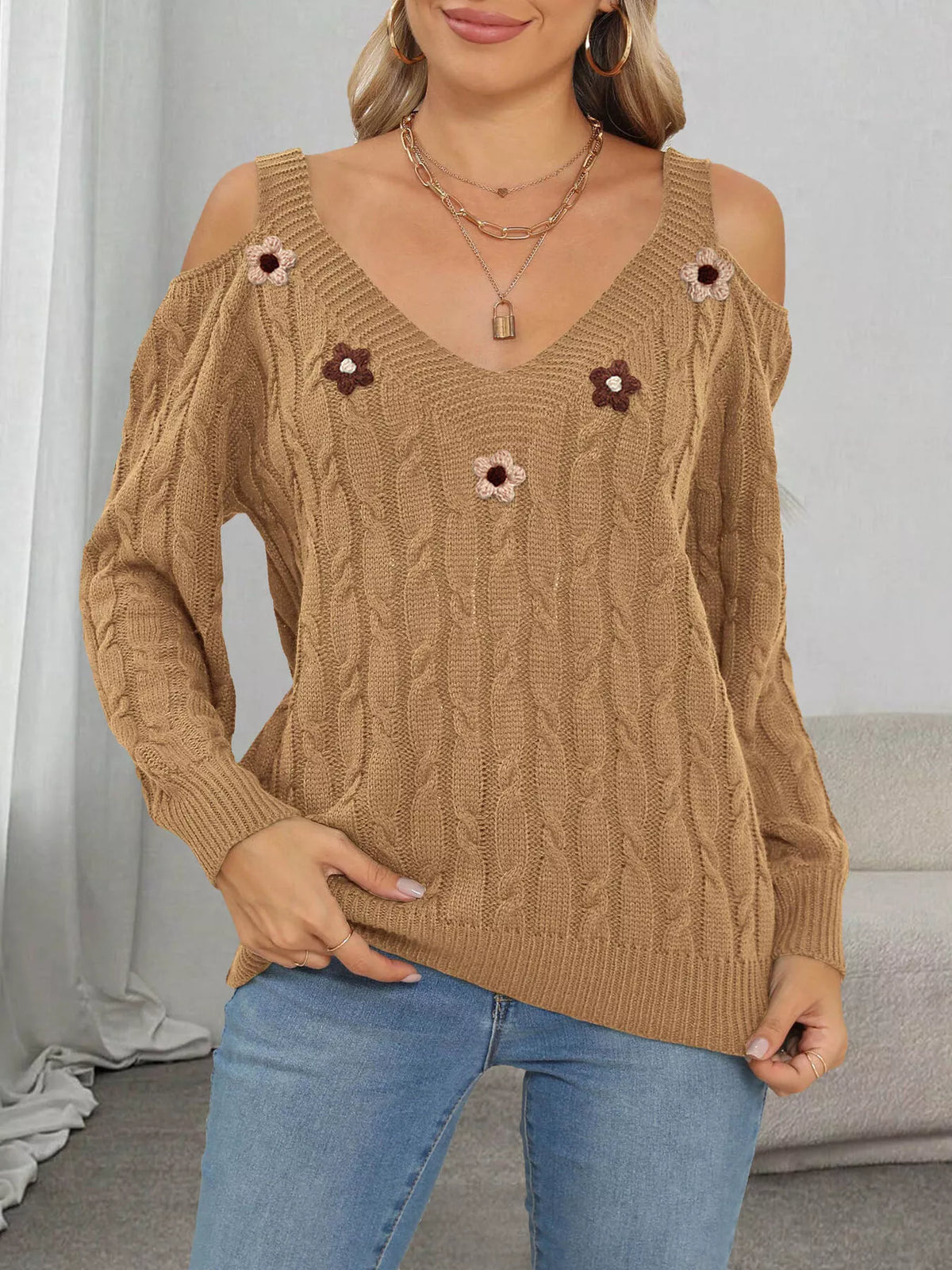 Tan cable-knit sweater with pink and brown floral appliqués, front view