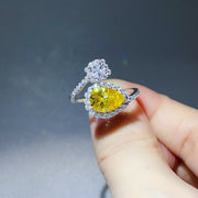 Yellow pear-shaped bypass ring with clear-stone cluster held between fingers