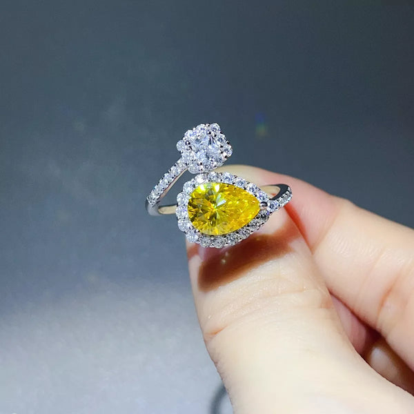 Yellow pear-shaped bypass ring with clear-stone cluster held between fingers