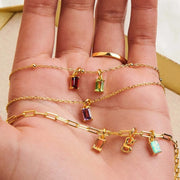 Several colourful rectangular pendant necklaces draped across an open hand