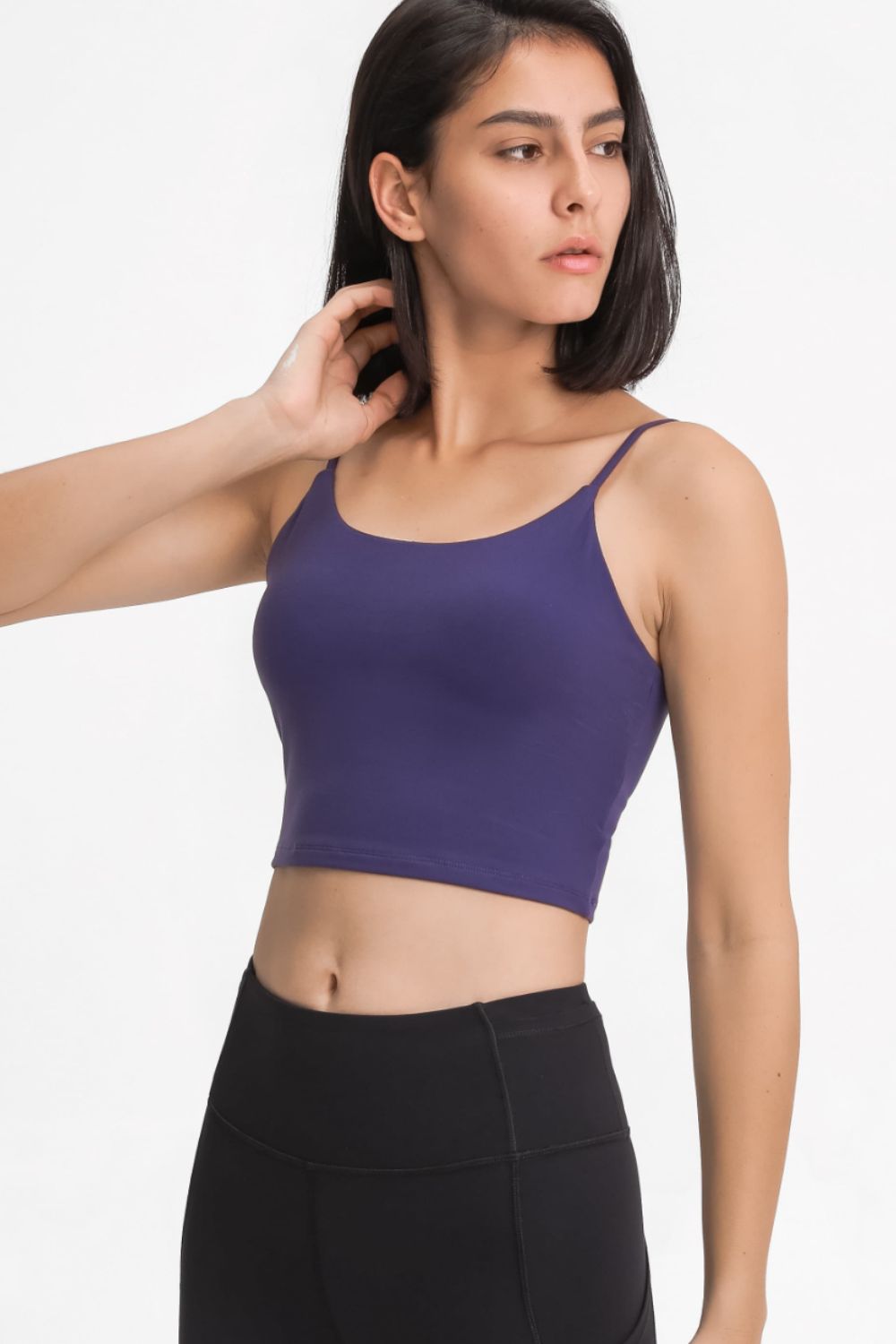 Front three-quarter view of a model in a purple cami and black leggings.