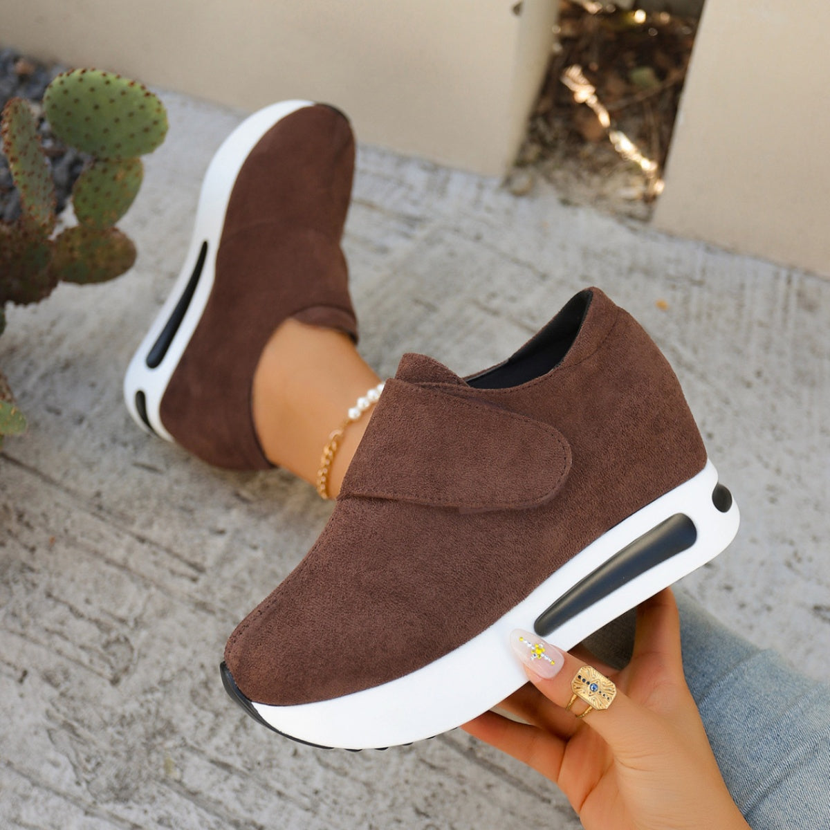 Brown slip-on platform sneaker held in hand, showing dark outsole
