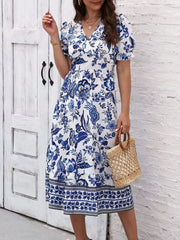 Front view of the blue and white floral midi dress with a V-neckline and raised-hand pose.
