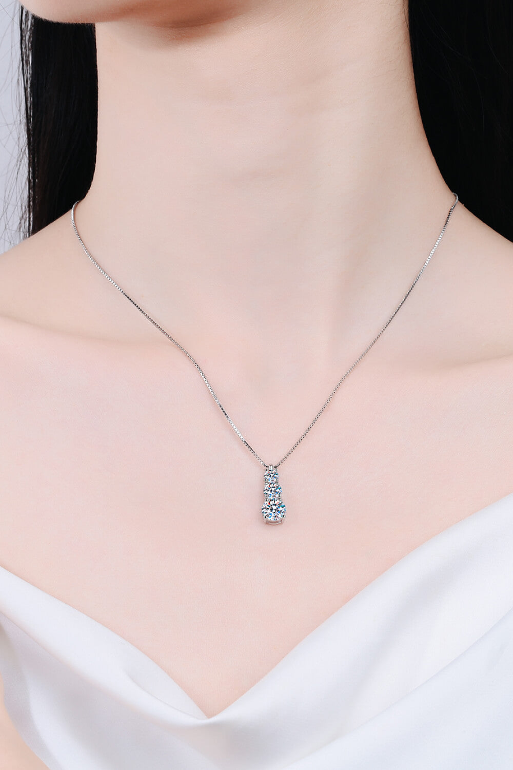 Model wearing a delicate vertical three-stone pendant necklace