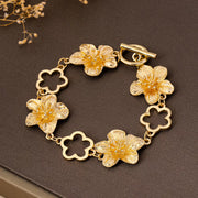 Gold-tone flower bracelet with open flower-shaped links on dark background
