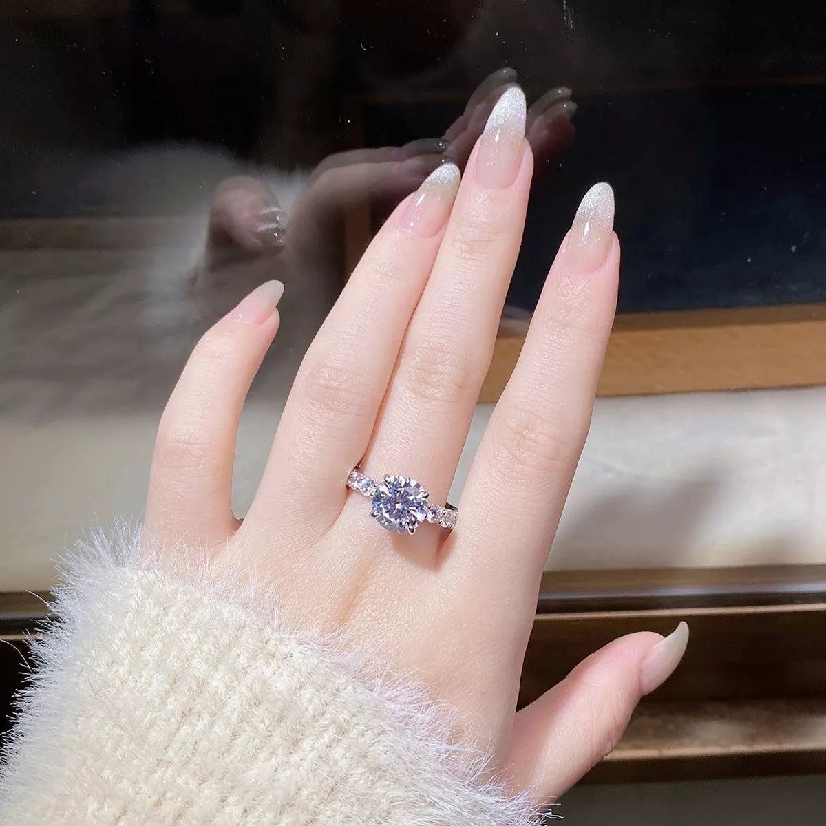 Silver-tone ring with a large round clear stone and sparkling accents worn on a hand.