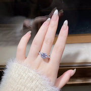 Silver-tone ring with a large round clear stone and sparkling accents worn on a hand.