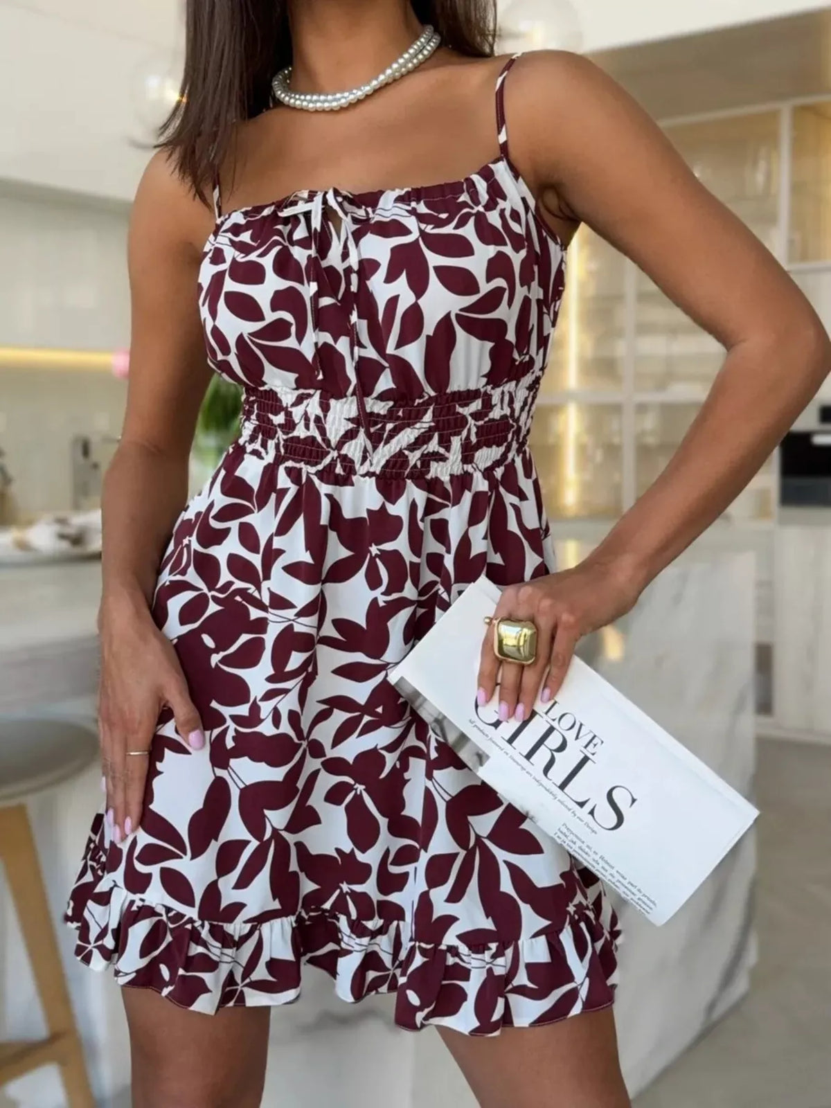 Model wearing the burgundy abstract-print spaghetti-strap mini dress with a flounced hem.