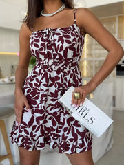 Model wearing the burgundy abstract-print spaghetti-strap mini dress with a flounced hem.