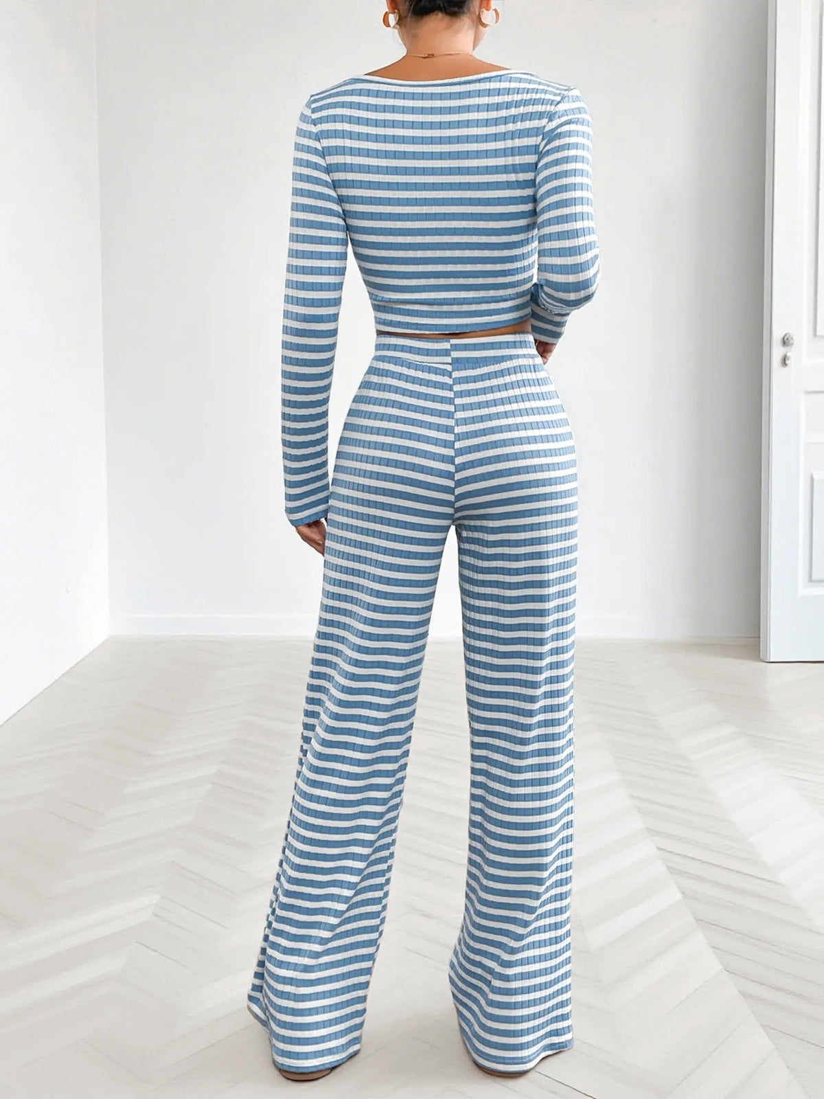 Model sitting on a sofa in blue striped lounge pants and crop top