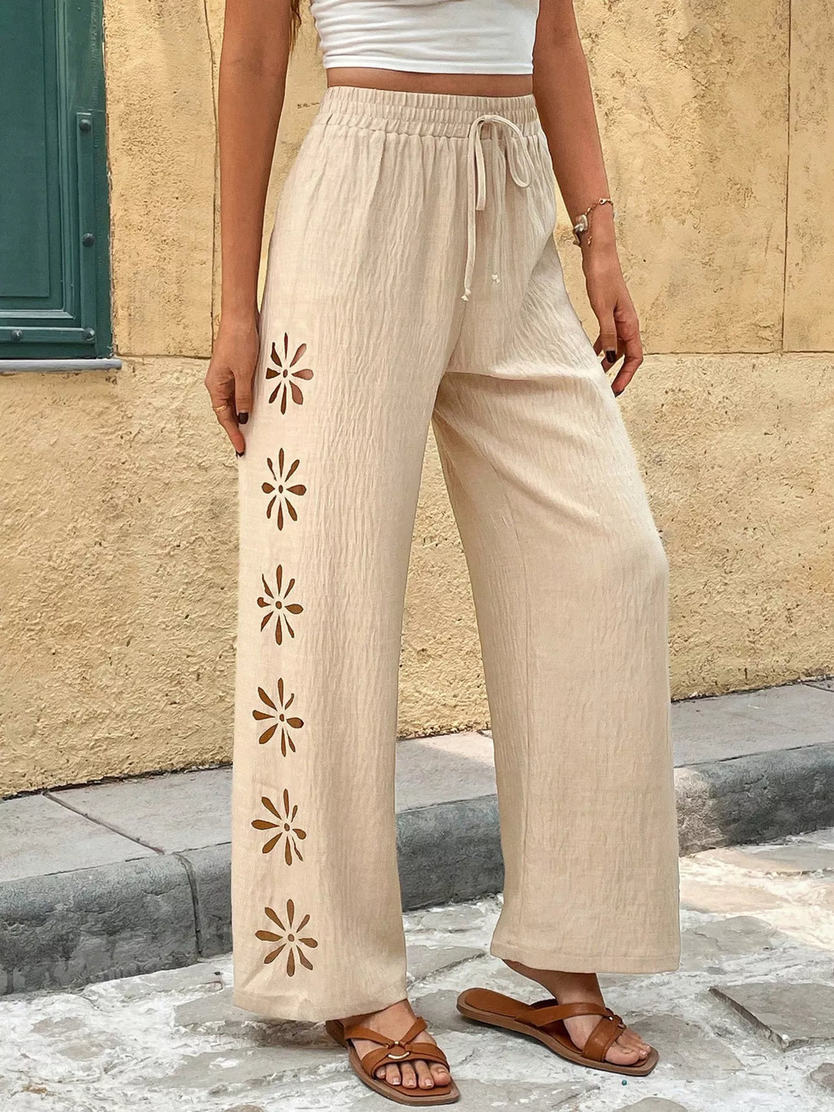 Close view of cream pants with embroidered flower cutouts