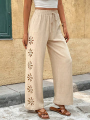 Close view of cream pants with embroidered flower cutouts