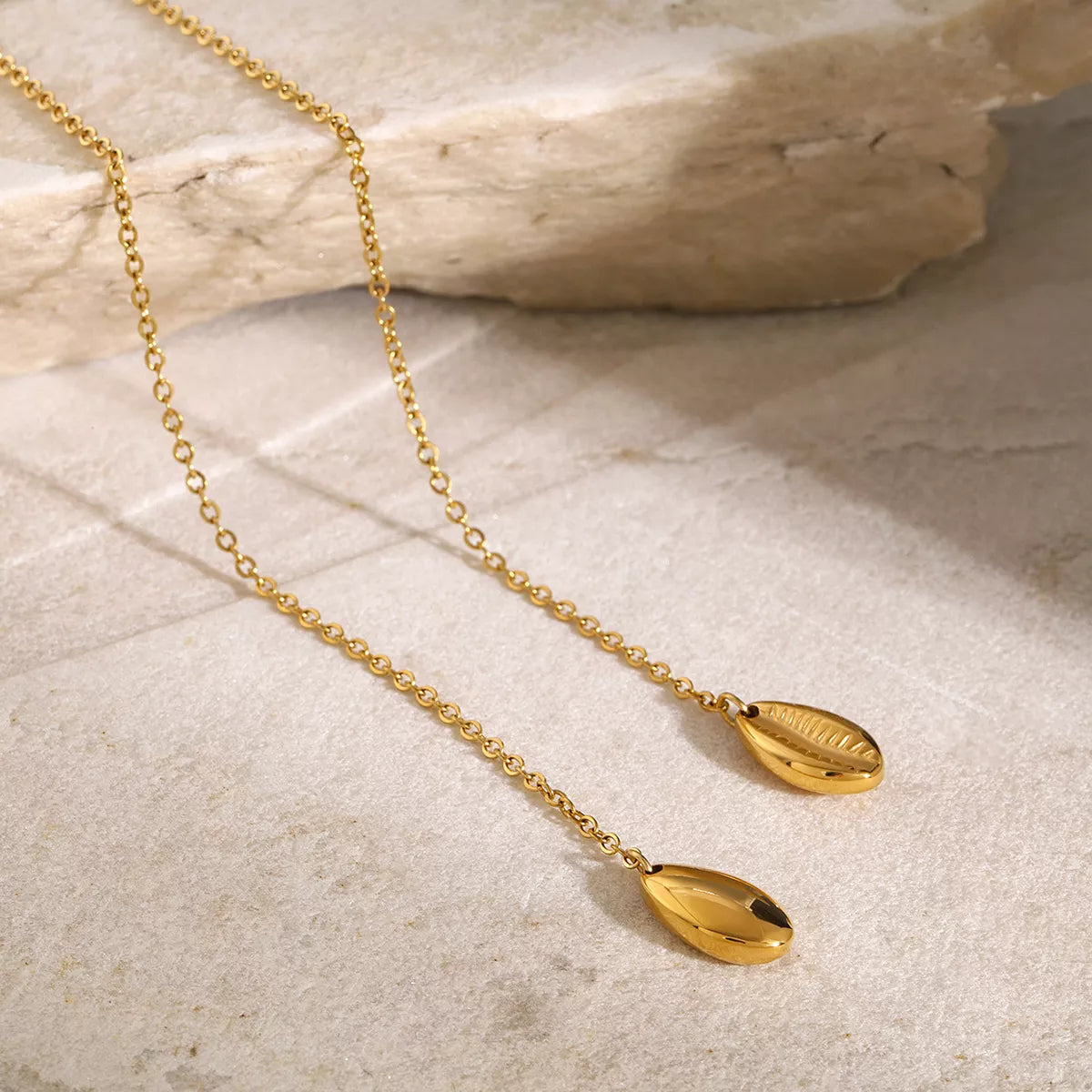 Gold Y-shaped necklace arranged on a pale stone surface