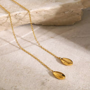 Gold Y-shaped necklace arranged on a pale stone surface