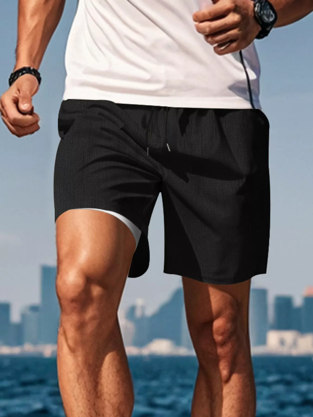 Man wearing black drawstring shorts by the water