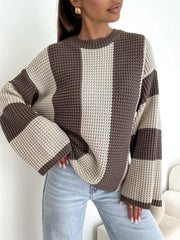 Front view of cream and taupe sweater with hands gathered at the hem