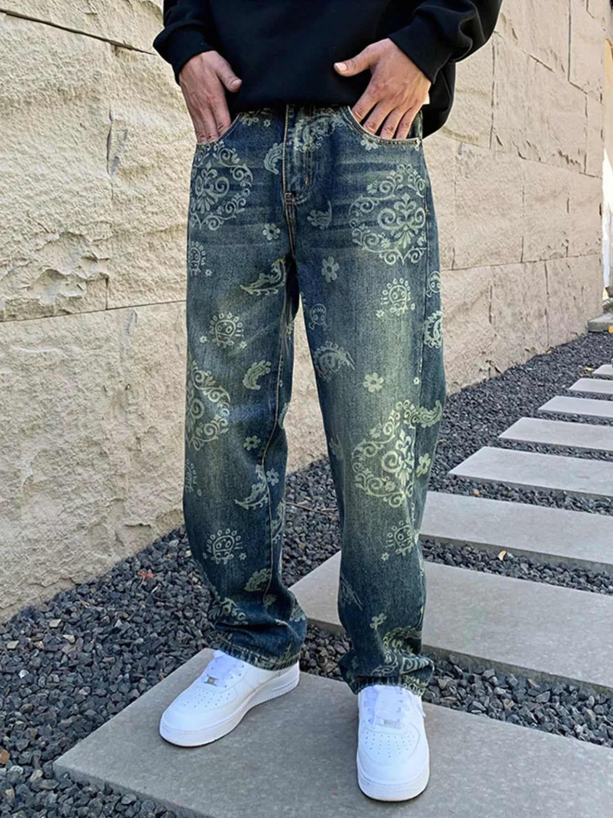 Front view of men's loose blue jeans with faded ornamental and floral patterns