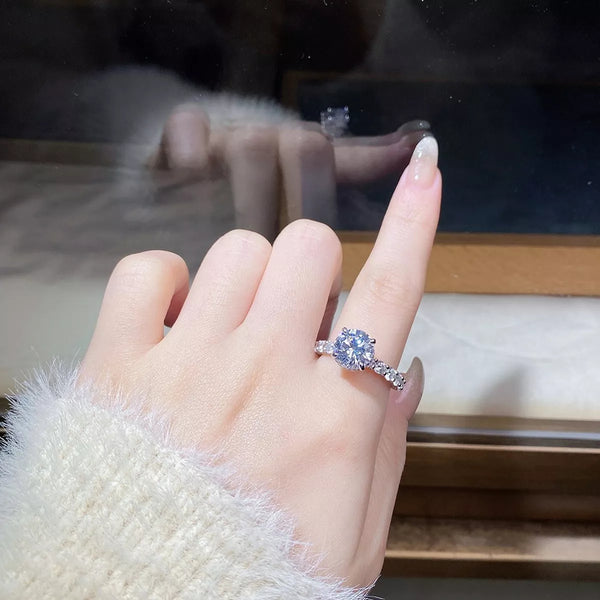 Close view of a round-stone silver-tone ring worn on a finger.