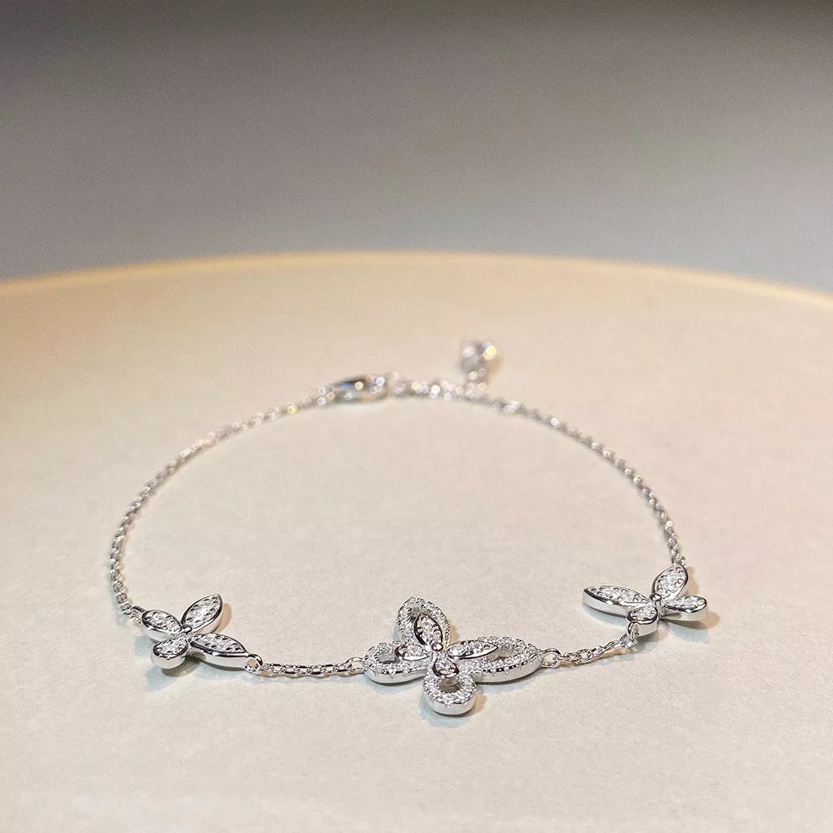 Chain bracelet with three clear-stone butterfly motifs shown at an angle