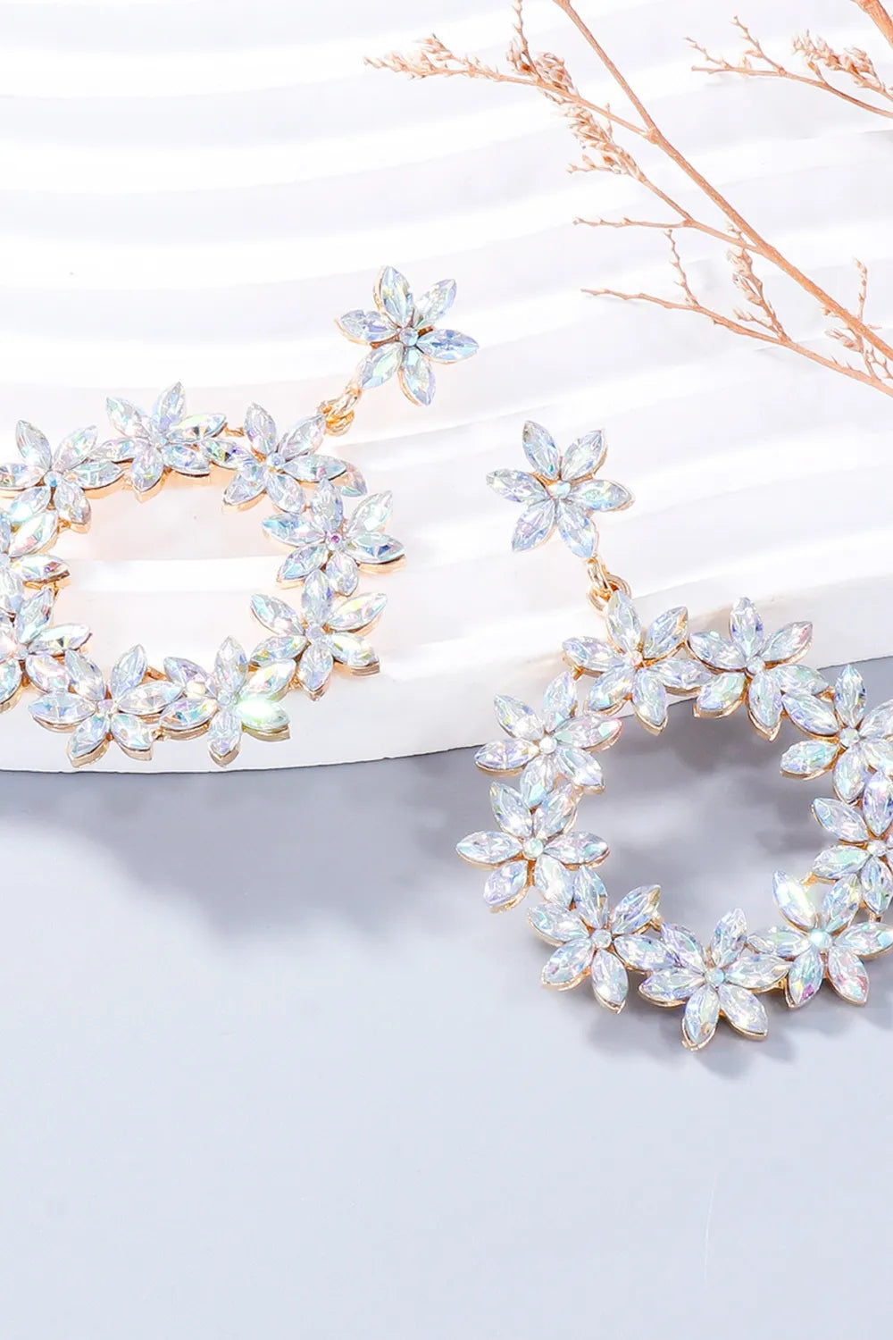 Pair of white rhinestone flower dangle earrings viewed at an angle
