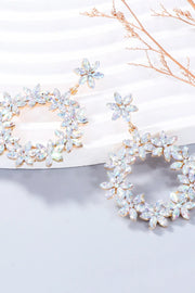 Pair of white rhinestone flower dangle earrings viewed at an angle