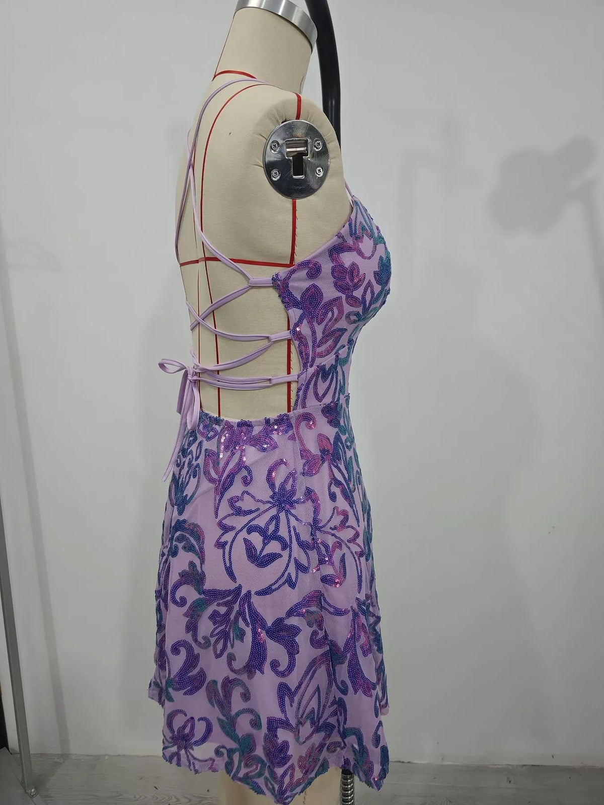Side view of the lavender sequin mini dress on a dress form, showing its open lace-up back.