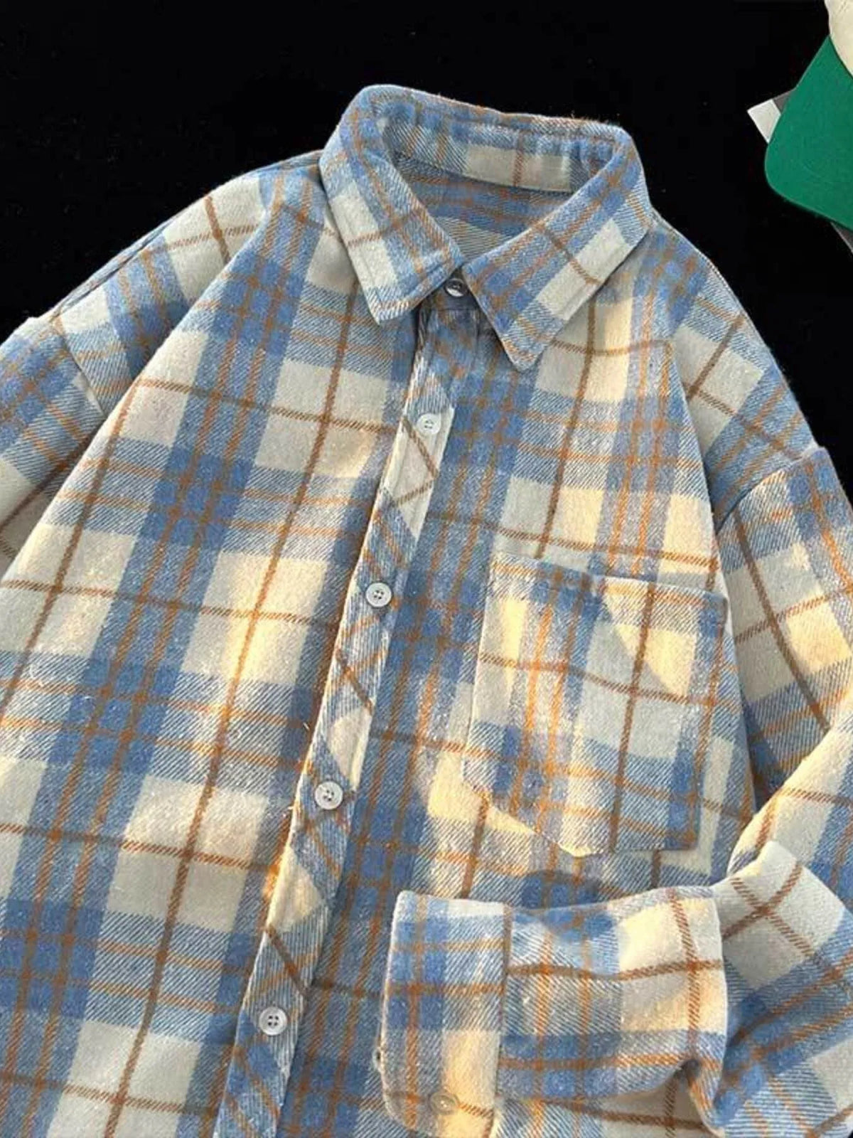 Full-length view of the oversized plaid button-up shirt showing its long sleeves and rounded hem