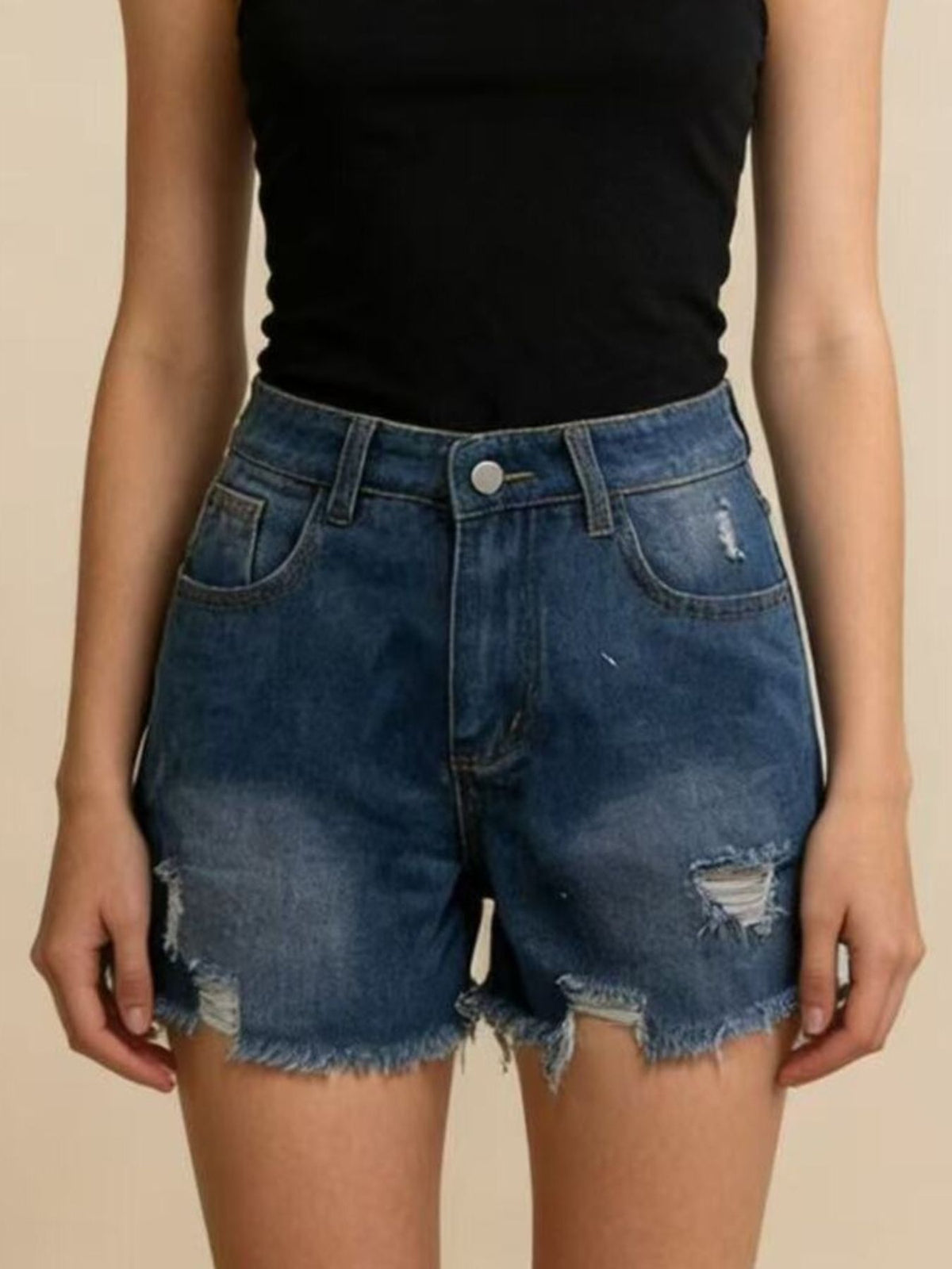 Front view of dark blue frayed-hem denim shorts with small ripped details, worn with a black top