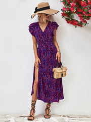 Purple printed dress modeled with a small woven handbag and straw hat.