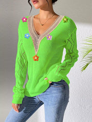 Angled standing view of the bright green floral sweater with one hand in a pocket.