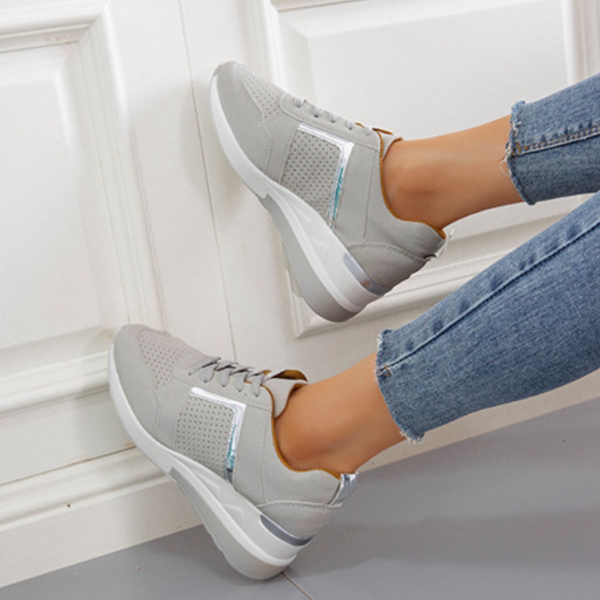 Gray wedge sneakers worn with jeans, side view