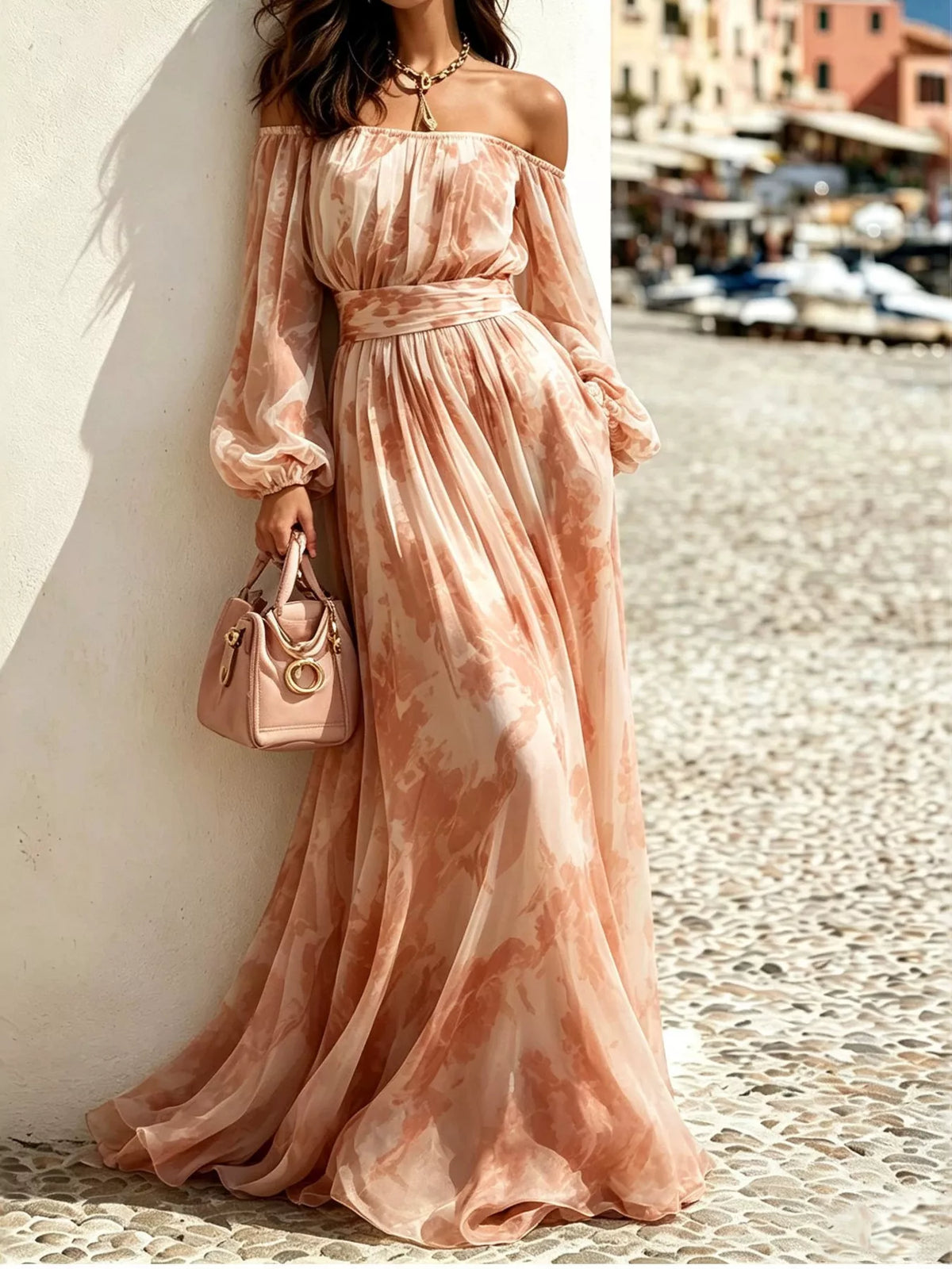 Peach patterned off-shoulder maxi dress with balloon sleeves, modelled beside a harbour