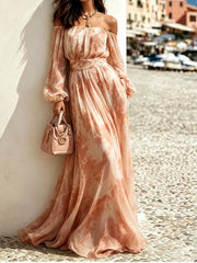 Peach patterned off-shoulder maxi dress with balloon sleeves, modelled beside a harbour