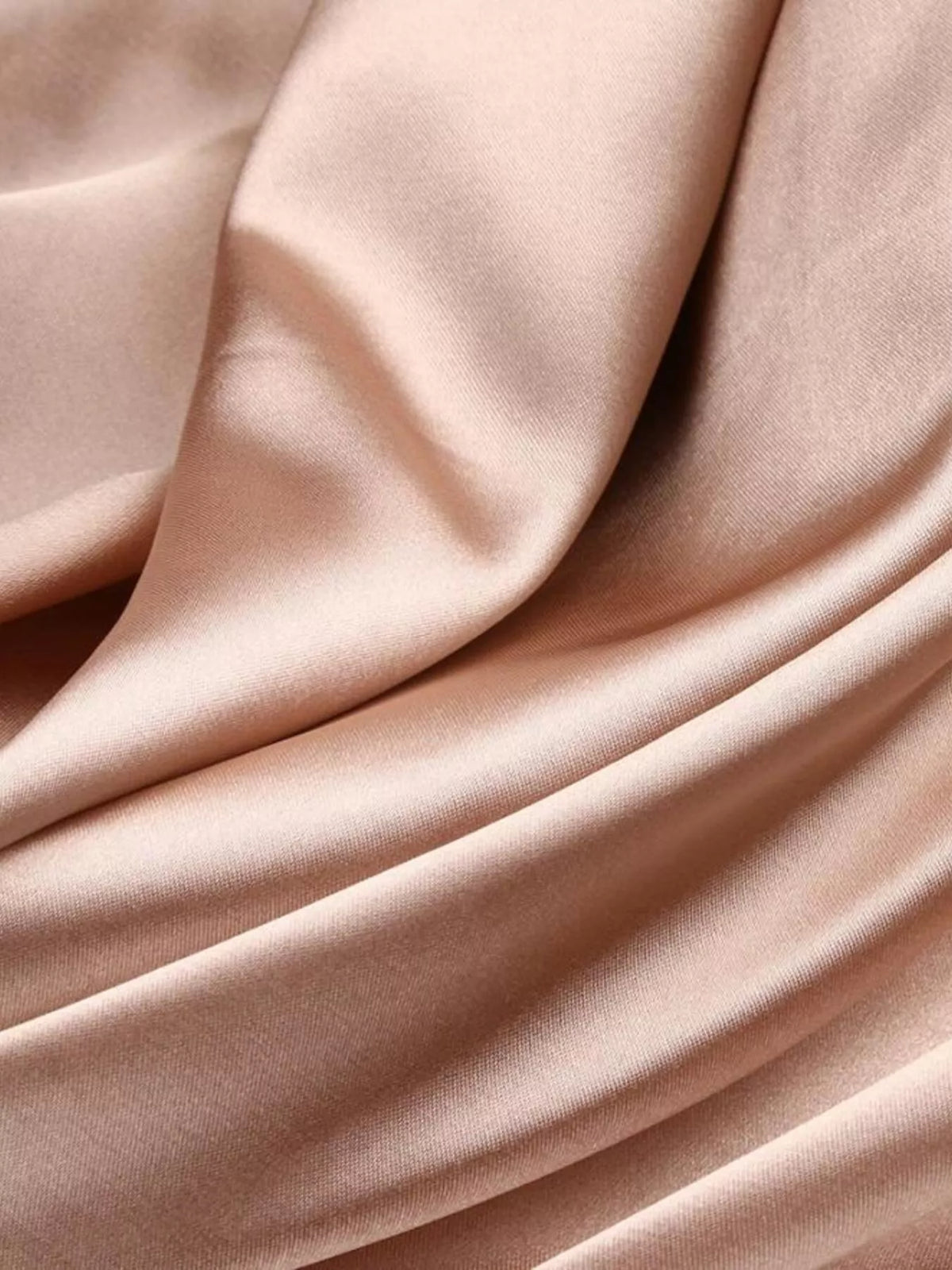 Close-up of the smooth blush fabric and soft folds of the maxi dress
