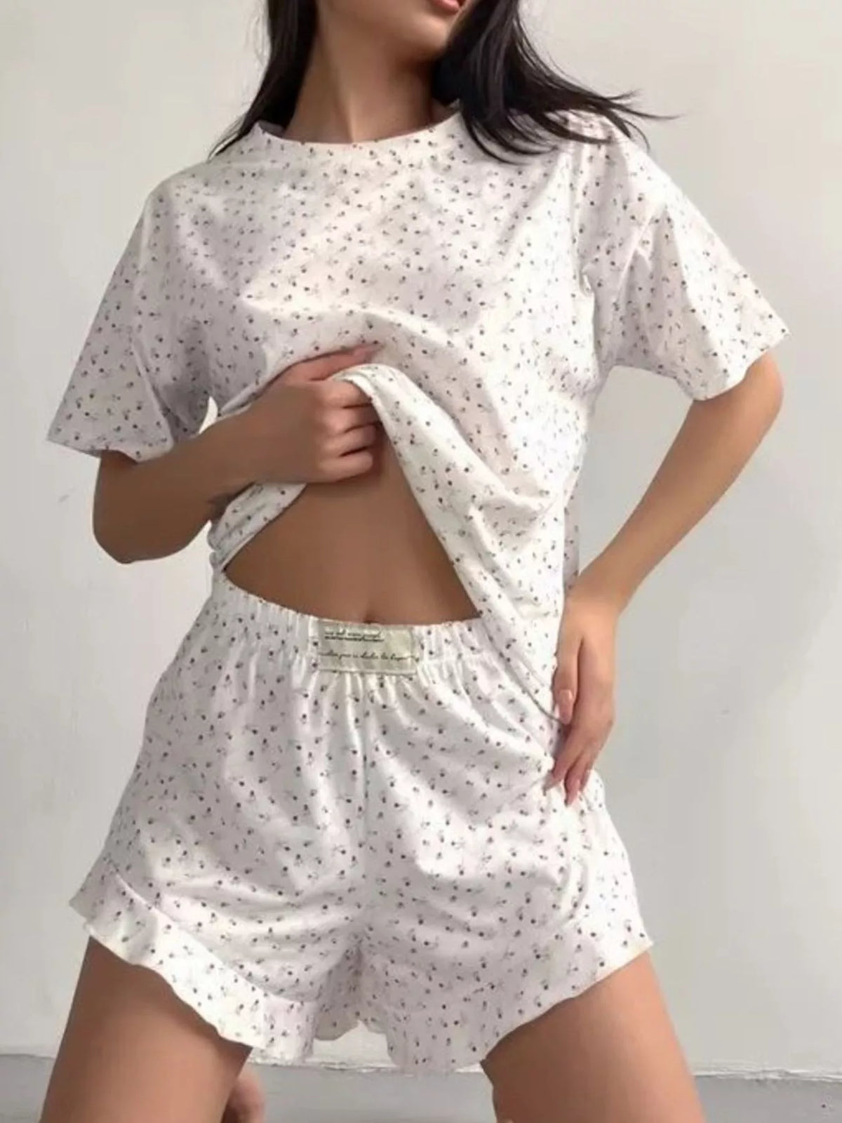 Model wearing white floral short-sleeve top and ruffled shorts lounge set