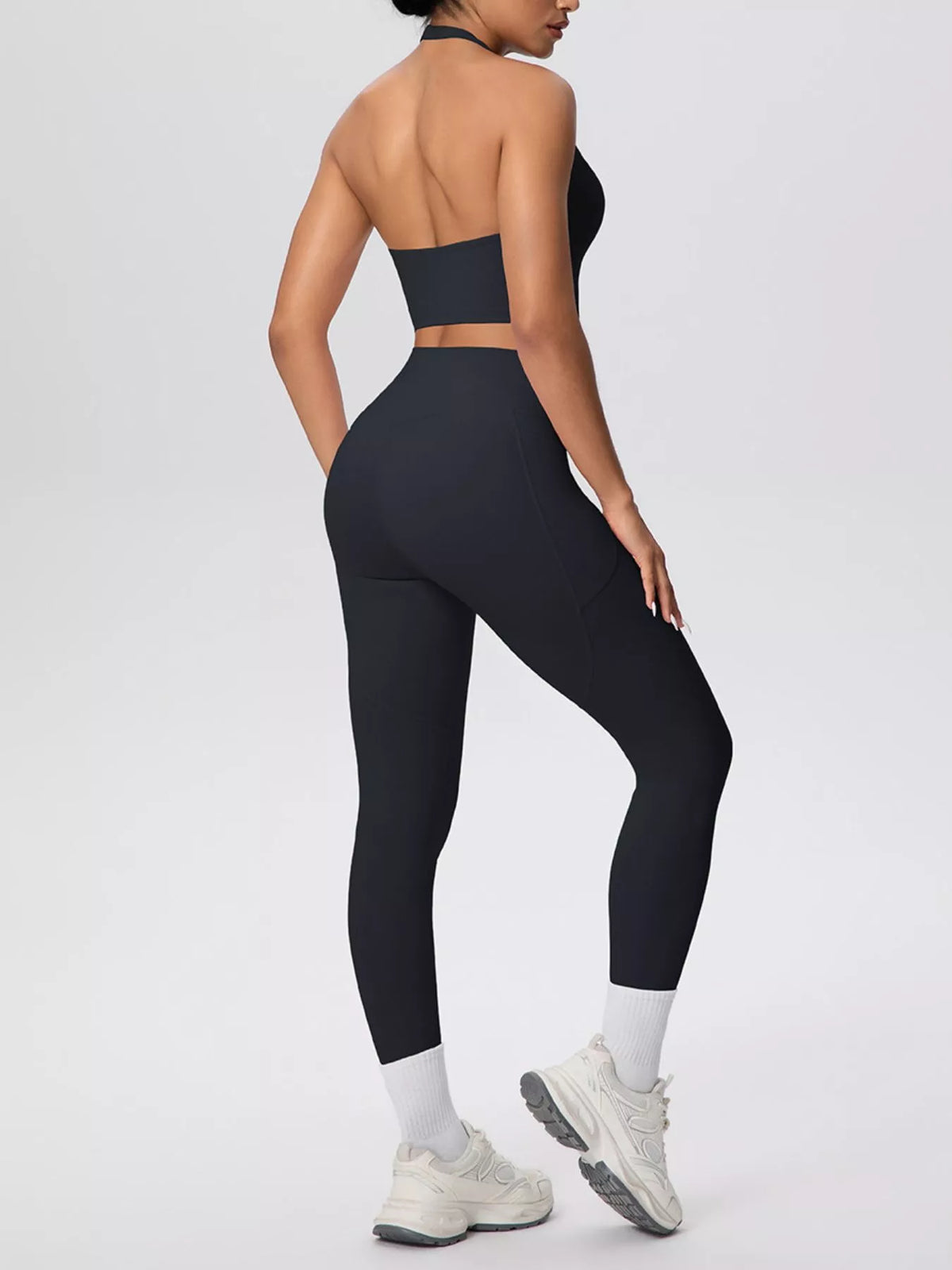 Rear angled view of black halter top and high-waisted leggings