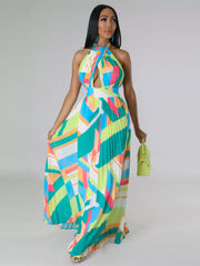 Turquoise, yellow and pink pleated halter dress on a model holding the skirt beside a green handbag.