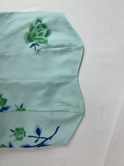 Close-up of pale green dress fabric and embroidered blue flower.