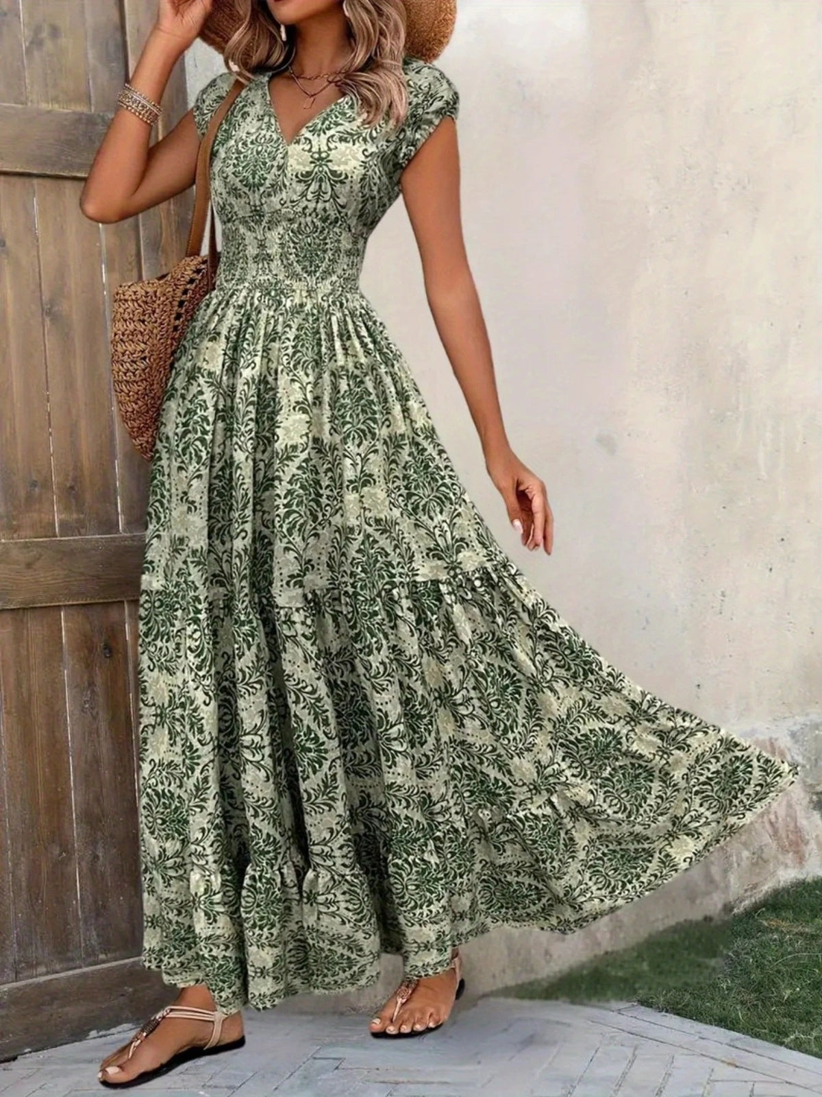 Green floral maxi dress on a model, with the full tiered skirt sweeping to one side.