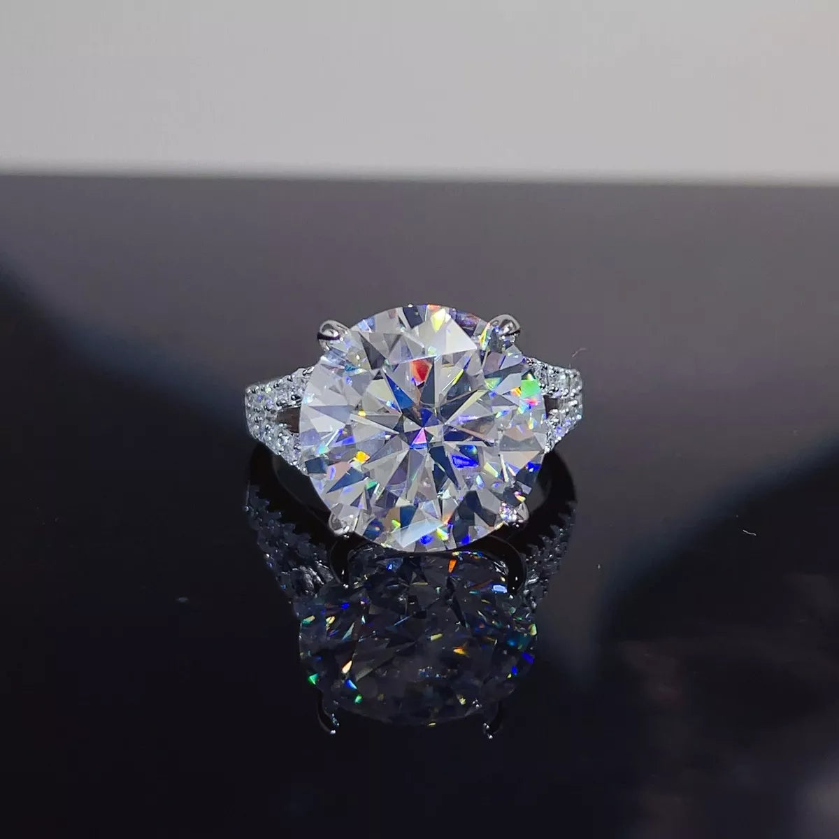 Round solitaire moissanite ring with a pavé-style band displayed on a dark surface