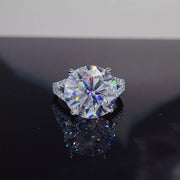 Round solitaire moissanite ring with a pavé-style band displayed on a dark surface