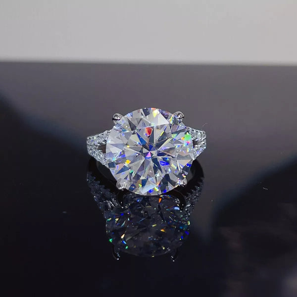 Round solitaire moissanite ring with a pavé-style band displayed on a dark surface