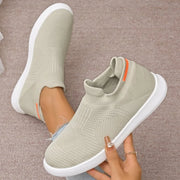 Sage green mesh sneaker held to show sole