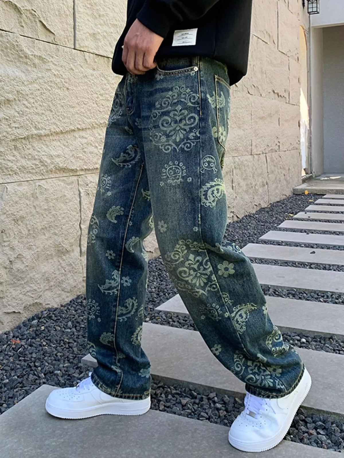 Angled side view of blue jeans with pale ornamental motifs