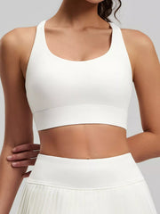 Front view of white scoop-neck active bra with a wide band and matching pleated skirt