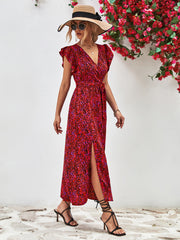 Red printed dress with a thigh-high slit, modeled with a straw hat and handbag.