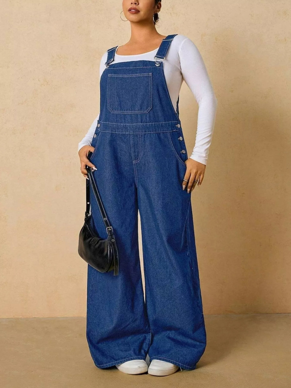 Medium blue wide-leg denim overalls, full-length front view over a white long-sleeve top.