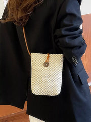 Woven mini bag worn crossbody over a dark jacket