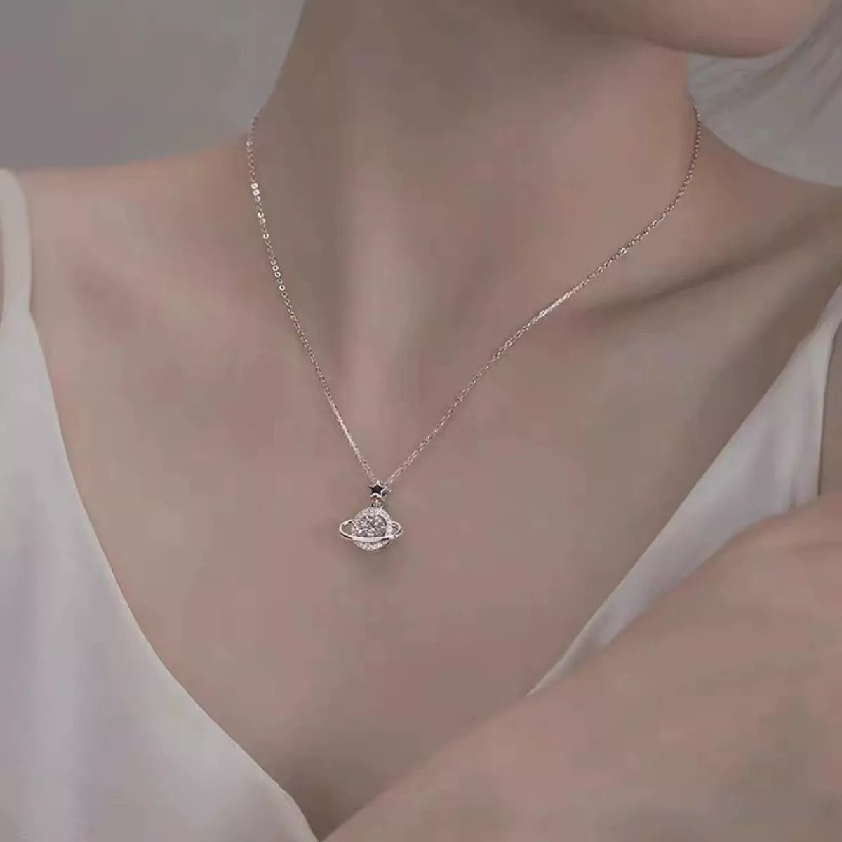 Silver planet pendant necklace worn at the neckline